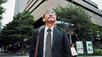 Business man, city and thinking on travel, location and search for direction with low angle in street. Mature person, outdoor and commute to workplace with reflection, inspiration and road in Japan