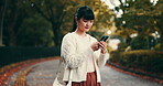 Woman, phone and park for social media in Japan, travel and tourist in garden for sightseeing. Female person, reading message and online for communication, texting and vacation for internet update
