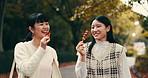 Asian women, cheers and friends eating street food, walk or happy on commute to travel to Japan. Girls, together or smile with snack outdoor or dango at park for vacation, toast or tourist on holiday