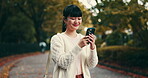 Woman, phone and park for chat in Japan, travel and tourist in garden for sightseeing. Female person, reading message and online for communication, nature adventure and vacation for internet update