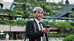 Mature businessman, phone and travel in city with texting, reading and notification on commute to work. Person, smartphone and happy with mobile app, email and contact on urban sidewalk in Japan