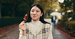 Street food, eating and happy with Japanese woman in park for dessert, traditional cuisine and holiday. Dango, taste and festival season with asian person and culture snack for sweets and lunch