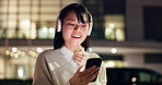 Asian woman, headphones and night with phone in city for online browsing, app or research. Japanese, female person or user thinking with mobile smartphone for news, social media or network in town