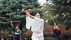 Bamboo, Kendo and sword with Japanese instructor in forest for martial arts class, practice or training. Culture, demonstration or exercise and serious Samurai group with Sensei in nature for skill