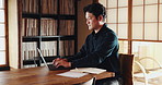 Writer, typing and man in home office with laptop, research notes or business plan for freelance project. Remote work, connectivity and Japanese person at desk writing email, article or online report