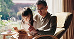 Asian father, child and reading book in family home for learning, education or talk to Japanese girl. Kid, dad and  parent storytelling together for help, teaching language or study for development