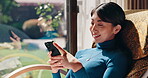 Japanese woman, happy and mobile phone for relax, social media and comfort on weekend in living room. Female person, technology and scroll for rest, news and online for communication in house on app