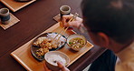 Hands, food and chopsticks with lunch for person in home with healthy meal, ramen and nutrition. Above, eating and dish for diet, wellness and hungry with rice, vegetables and snack at house in Japan