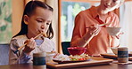 Asian girl, eating and mother with chopsticks for food, meal or dinner together on table at home. Japanese, child or hungry kid with mom, bite or taste for dining tradition, lunch or snack at house