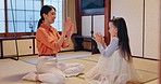Japanese woman, child and clapping game in home for learning, coordination development and traditional culture. Family, girl and happy in living room with heritage, fun activity or dexterity with mom