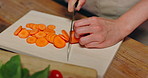 Hands, knife and carrots on chopping board for diet in kitchen, home or cooking organic vegetables for dinner. Person, chef and cutting ingredients for nutrition, food or gut health at house in Japan