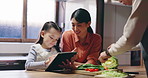 Mother, child and tablet in home for cooking, learning recipe and organic vegetables. Happy mom, dad and kid with technology in kitchen for teaching Japanese girl, education and family watch video