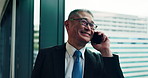 Mature businessman, phone call and window in office with smile, contact or negotiation for deal at company. Person, smartphone and talk for consulting, lead or advice at insurance agency in Japan
