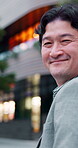 Businessman, travel and face in city for commute, location and walking to destination with happiness. Executive, portrait and Asian person for international trip, smile and positive mood in Japan