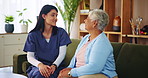 Elderly care, nurse and old woman on sofa with conversation, support or comfort at nursing home. Homecare, senior person and caregiver on couch with healthcare, discussion and advice in living room