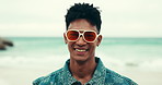 Beach, face and man on holiday, nature and happy with sunglasses, travel and free time on vacation. Outdoor, sea and person with shades, smile and trip to relax, ocean and calm on getaway and Florida