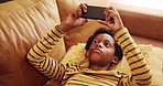 Home, boy and black child with phone for games, connection or streaming cartoon movies on sofa. Entertainment, relax or kid gaming on couch with mobile for watching video, playing online or addiction