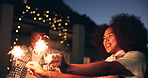 Friends, sparkle and woman at night celebration with dancing, fun bonding or excited at social event. Outdoor, lights and happy people with fireworks for new year party, festival or cheers with smile