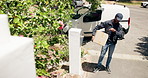 Courier, man and check watch for delivery with time management, impatient and waiting for customer outdoor. Package distribution, black worker and box by house for online order and shipping service