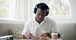 Reading, cafe and black man with headphones and books for learning, studying and education. School, coffee shop and student listening to music with textbooks for knowledge, assessment and project