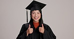 Happy graduate, woman or student with thumbs up at studio for success, learning achievement or excellence. Face, college graduation or Asian person with like hand gesture on gray background in Taiwan