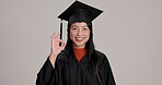 Face, graduation and happy woman with ok sign in studio for success, learning goal and academic excellence. Portrait, graduate and college student with okay hand gesture on gray background in Japan