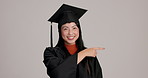 Pointing, mockup and face of woman graduate in studio for option, decision or choice with list. Happy, portrait and Japanese female student with presentation gesture for graduation by gray background