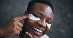 Face, black man and happy with eye pads for skincare, hygiene and glow in dark background. Male person, facial mask and smile or satisfied  with cosmetics product for self care and grooming