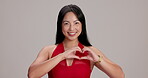 Face, heart hands and love with Japanese woman in studio on white background for valentines day. Flirting, portrait and smile of happy Asian person with emoji for affection, health or wellness