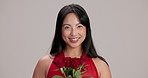 Smile, face and woman with roses in studio for valentines day, anniversary or romantic gift. Happy, present and portrait of Japanese female person smelling bouquet of red flowers by gray background.