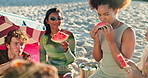 Beach, group and friends with watermelon, vacation and bonding together with happiness. Seaside, ocean and people with summer holiday, adventure and relax with snack, fruit and eating with smile