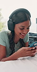 Headphones, cellphone and woman on bed in home listening to music for online blog review of album. Happy, audio tech and female person streaming playlist with phone for creative project in apartment.