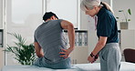 Man, patient and talking with physiotherapist for back injury, bad posture or muscle tension at clinic. Chiropractor, physio or therapist listening to client with sore spine for checkup at practice