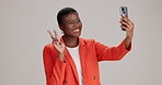 Phone, black woman selfie and peace sign with social media, smile and profile picture. Smartphone, hand gesture and person for online, dating or internet app on grey background studio mockup space
