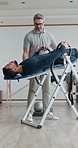 People, stretching and exercise as physiotherapist for fitness, wellness and strong muscle. Men, inversion table and coach for back pain, support and recovery in physiotherapy, workout and healthcare