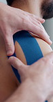 Hands, physiotherapy and tape on shoulder for healing, recovery and treatment for injury. Athlete, therapist and plaster in practice for kinesiology, fitness improvement and mobility in sports person