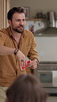 Acting, man and friends playing a game in home with description, answer clues and explaining with gestures. Entertainment, person and card for challenge, mime and guess activity for competition fun