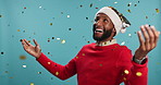 Christmas dance, face or man with confetti, party celebration or smile in studio on blue background. African, portrait or excited person with sales discount or event with joy, Xmas hat and winner