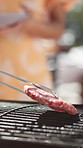 Person, hands and patty on grill at bbq with meat, tongs or prepare for cooking at social event in home. Party, food and fire for barbecue or heat for new year celebration with friends in closeup