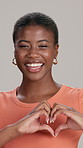 Heart hands, face and black woman in studio, background and gray background for emoji. Smile, female model and finger shape for love, thank you and support with peace and care or sign of kindness
