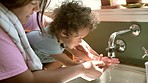 Cleaning, washing hands and mother with baby with water for hygiene, child development and wellness. Family home, teaching and mom with kid by sink with soap for health, bacteria protection and germs