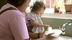 Cleaning, washing dishes and mother with child in kitchen for learning, child development and chores. Family home, housework and mom bonding with baby by sink with plates, soap and sponge for hygiene