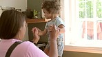 Child, girl and playing with mother on kitchen counter for bond or fun at house for development with parent. Family, children and woman is holding kid for bonding and love at house with happiness.