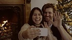 Couple, video call and wave at Christmas for talking, communication or festive wish in home living room. Happy man, woman and webinar with smile, hello or holiday by tree, culture and xmas tradition