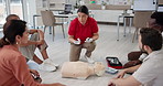 Office, first aid emergency and training people, explain and learning to use equipment on dummy. Workplace, floor workshop and instructor speaking to group, medical support and paramedic coaching