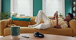 Happy man, phone and texting to relax on sofa for rest or comfort on weekend in home on social media. Chilling, technology and male person with mobile on couch for calm peace and online dating on app