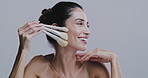 Beauty, makeup brushes and face of woman on gray background for wellness, makeover and cosmetics. Cosmetology, skincare and person with tools for facial application, salon and spa products in studio