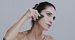 Gua sha, skincare and beauty with mature woman in studio for lymphatic drainage, wrinkle lift and glow. Facial massage, cosmetics and jade tool with person on white background for self care and spa