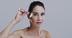 Jade roller, face and woman in studio for facial wellness, smooth skin and skincare massage. Dermatology, salon and portrait of person with tools for cosmetics, beauty or health on gray background