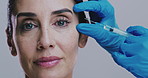 Plastic surgery, face and woman in studio for injection, facial and antiaging treatment. Surgeon hands, needle and mature person on white background for hyaluronic acid, collagen implant and filler